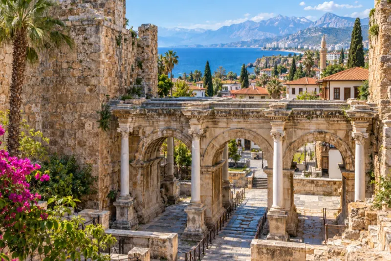 An ancient triple-arched Roman gate with a view over the blue bay of Antalya