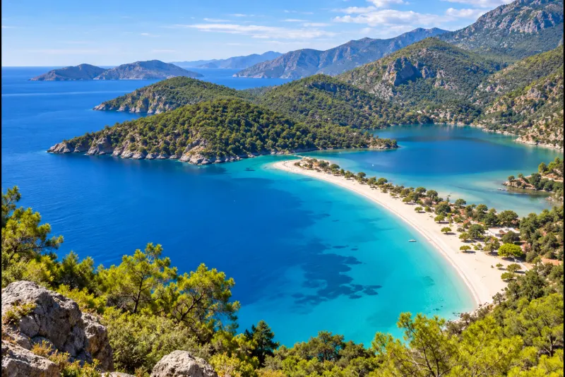 A crescent of white sand and turquoise lagoon beneath pine-covered mountains near Dalaman