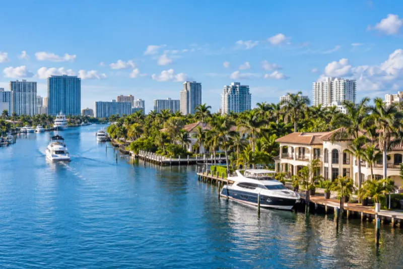 A waterway lined with palm trees, villas, yachts and apartment towers in Fort Lauderdale