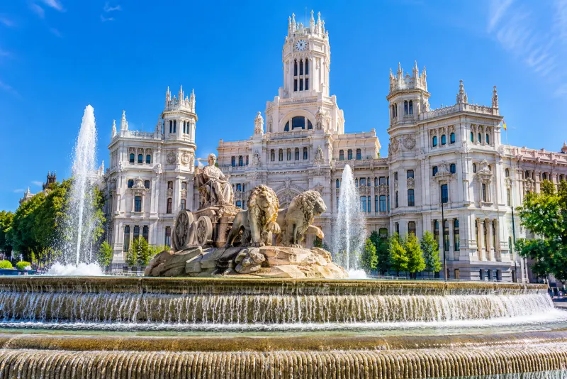 The Cibeles fountain with stone lions in front of a white palace in Madrid