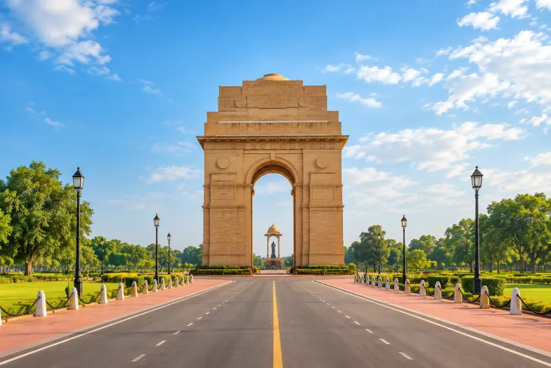 The sandstone India Gate arch at the end of a wide empty road in New Delhi