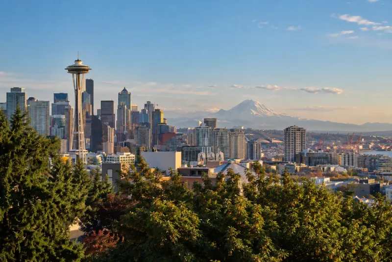 The Space Needle and downtown towers with a snowy mountain beyond at sunset in Seattle