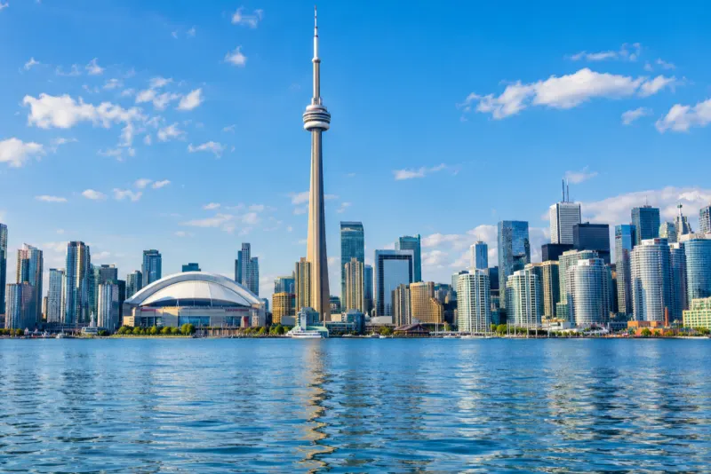 The CN Tower and a domed stadium behind the harbour water in Toronto