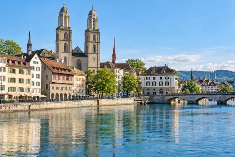 Twin-towered church and old riverside houses reflected in the water in Zurich